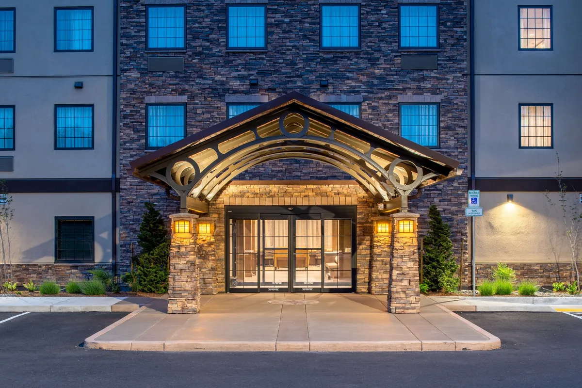 The image shows the hotel’s stone façade and arched, illuminated entrance, giving a strong sense of arrival and the welcoming atmosphere that greets guests returning from a day out. The lighting and architecture make it inviting for families coming back from local attractions.