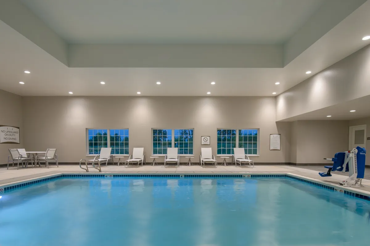 This image features the hotel’s indoor swimming pool area, complete with lounge chairs arrayed along the deck and large windows letting in soft natural light. The space invites guests to swim, relax, or socialize poolside in a calm atmosphere.